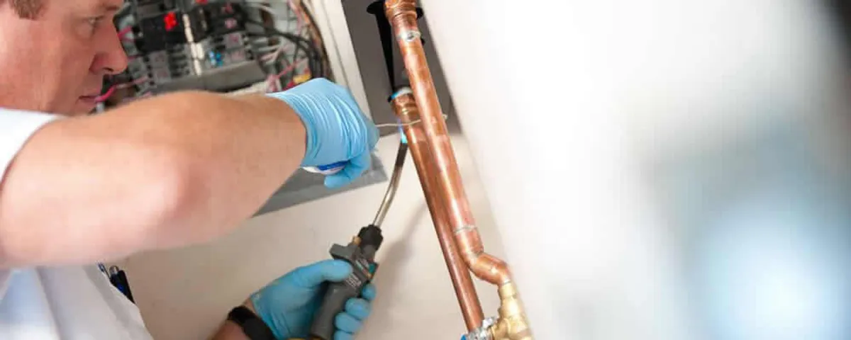 Water heater repair technician testing copper pipe connections and controls in Peoria, IL